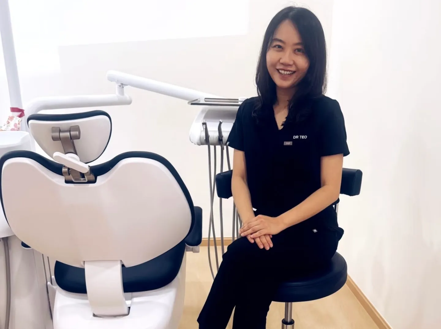 Dr. Teo seated beside the dental chair in a Heal Dental treatment room