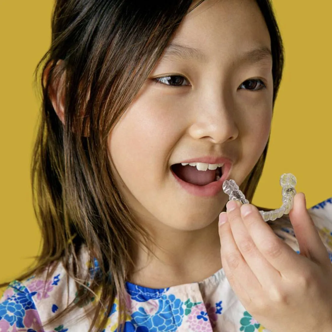 Child holding an Invisalign First clear aligner